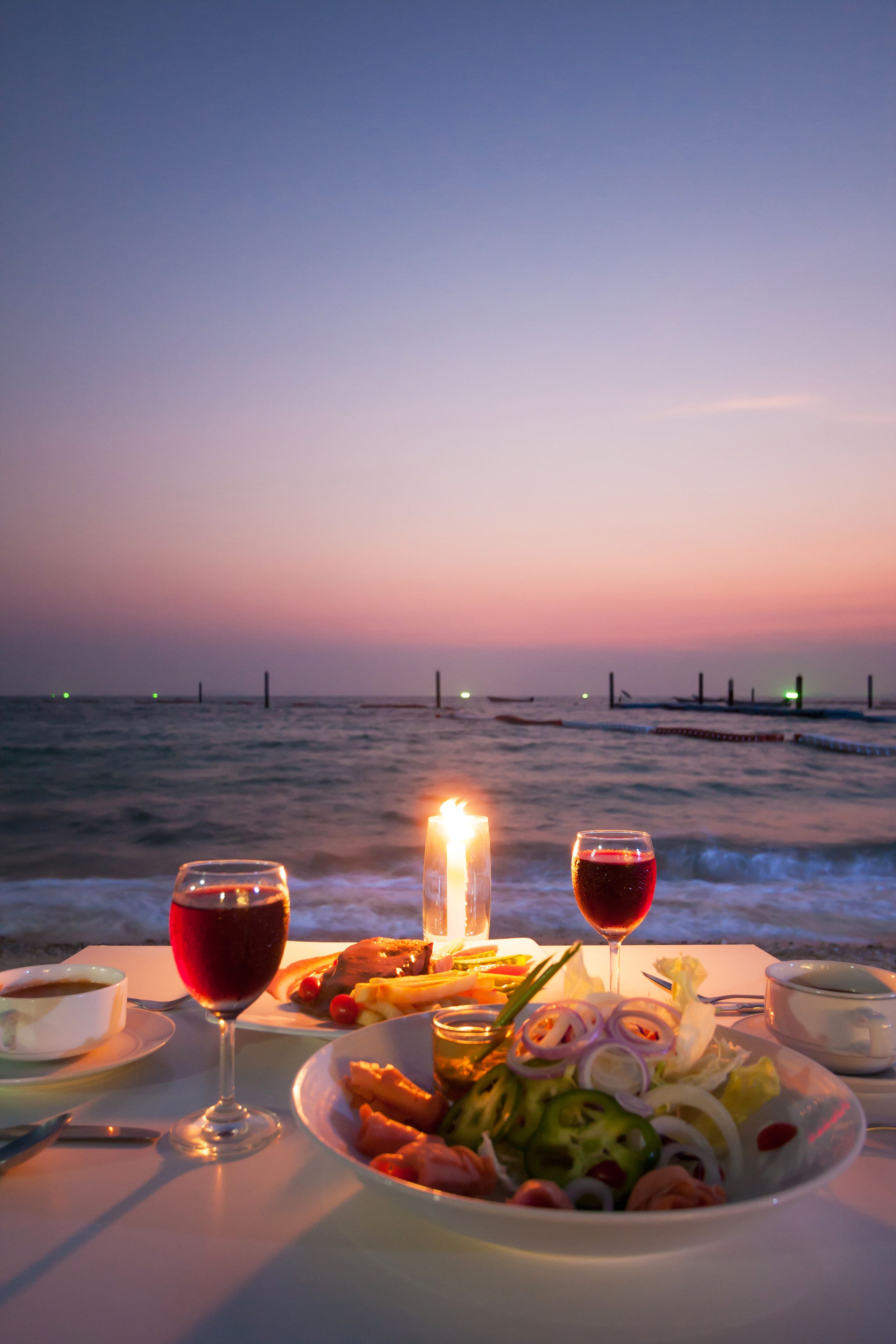 A table set for a meal with a view of the ocean at sunset.