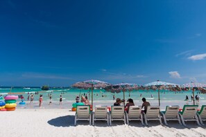 A beach with rows of sun loungers and colorful umbrellas. - Xanadu Beach Resort (Koh Lan)