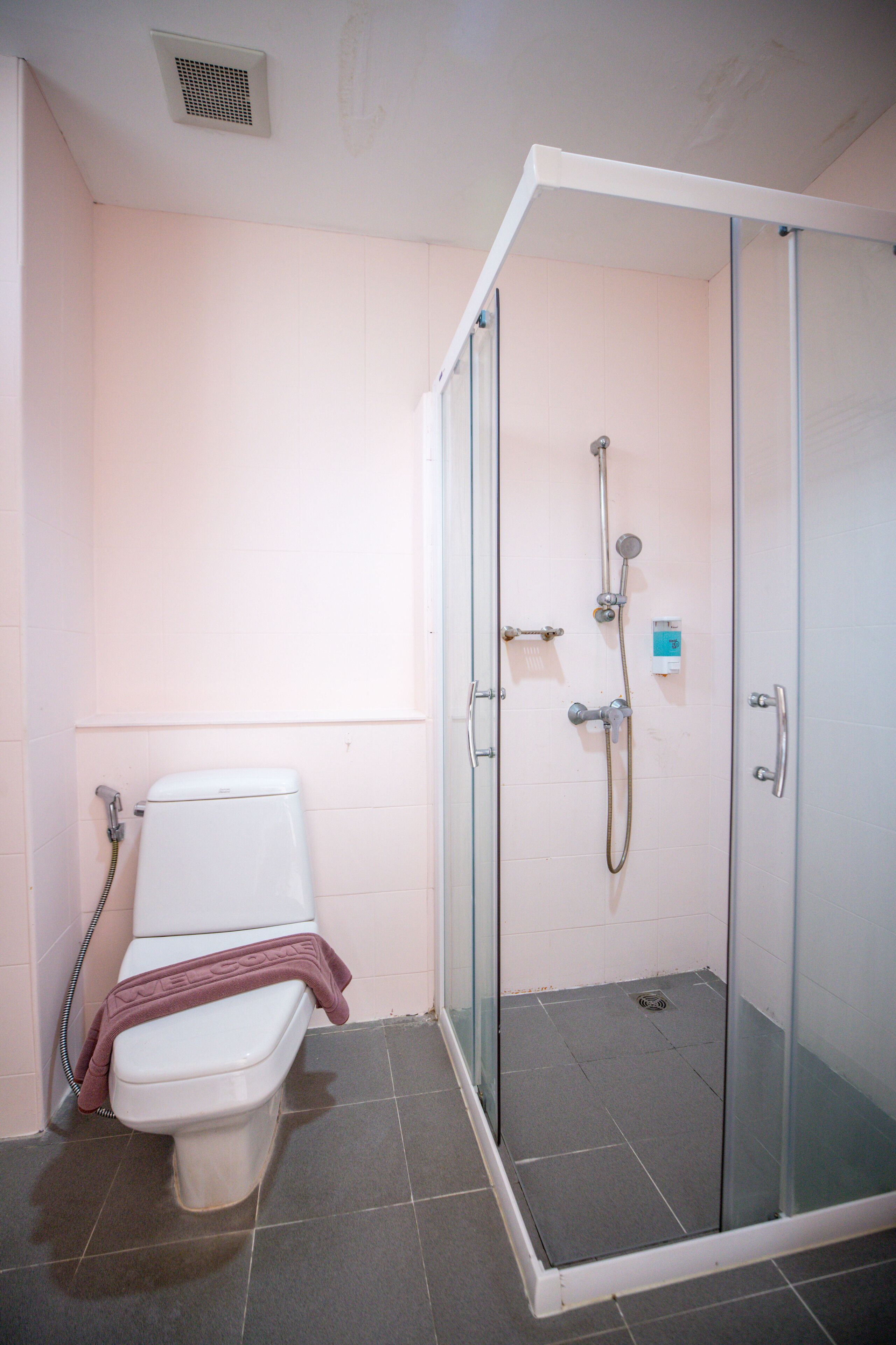 Un baño con inodoro, ducha y cabina de ducha con paredes de vidrio.