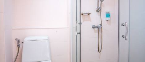 Un baño con inodoro, ducha y cabina de ducha con paredes de vidrio.