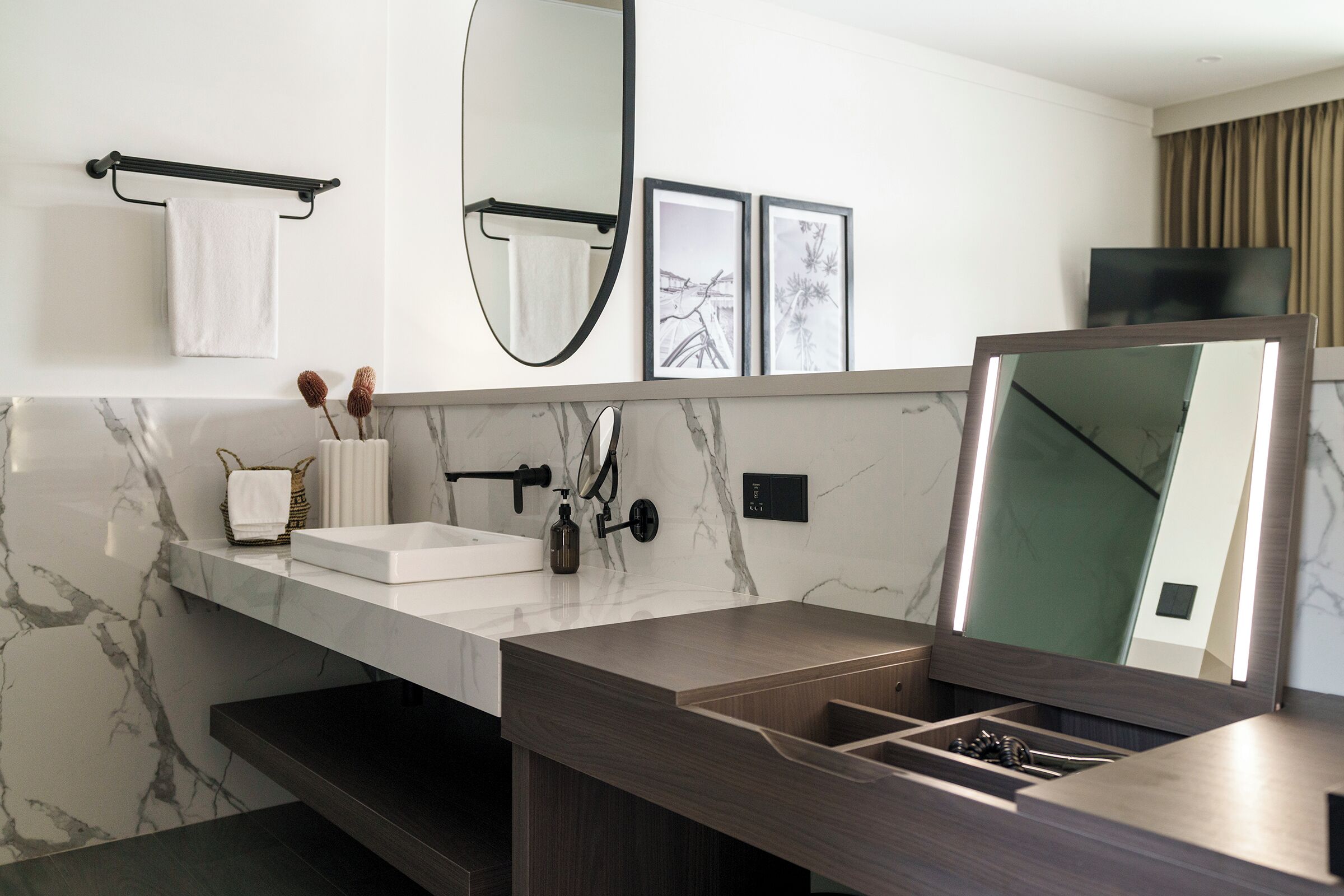 A modern bathroom with a marble vanity, a large mirror, and a towel rack.