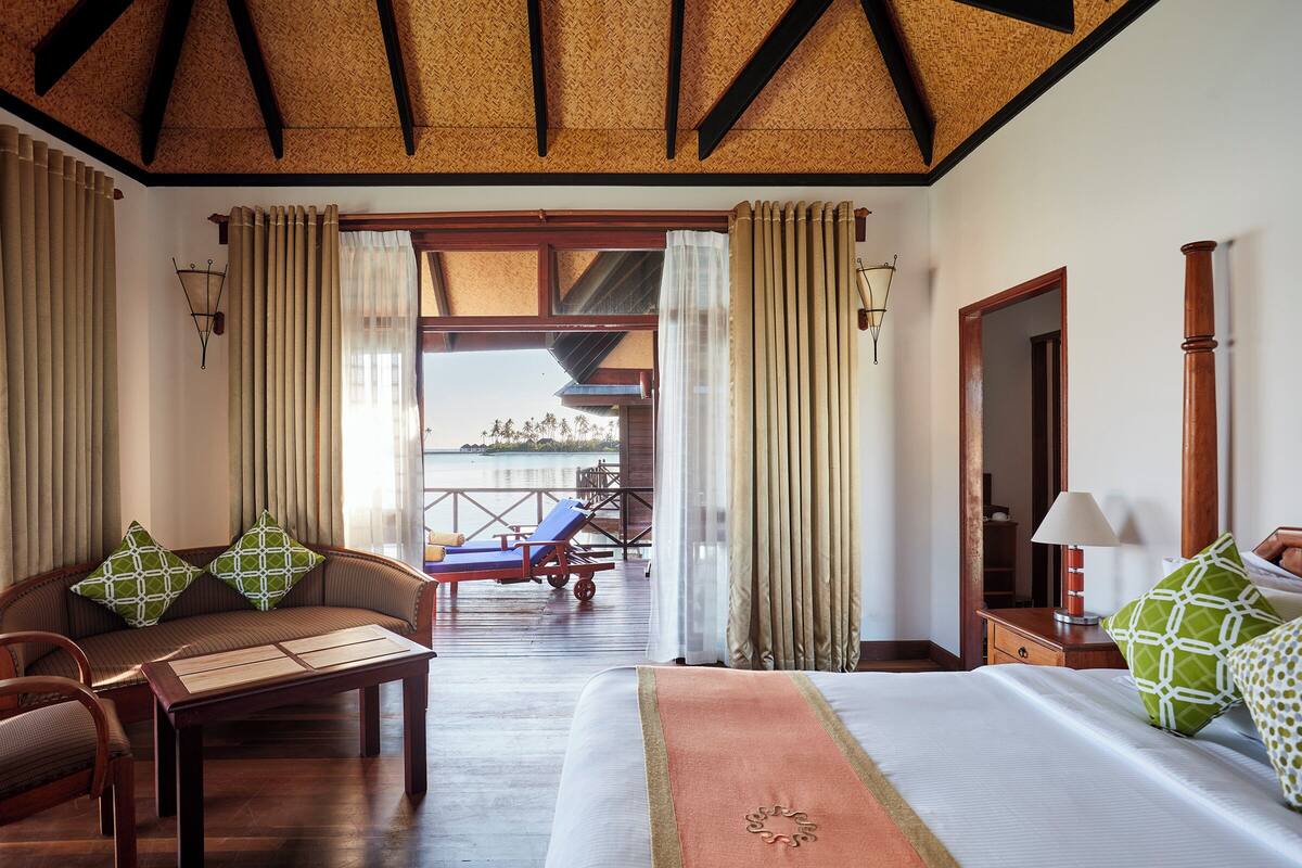 Una habitación de hotel con cama, sofá, mesa y vista al mar.