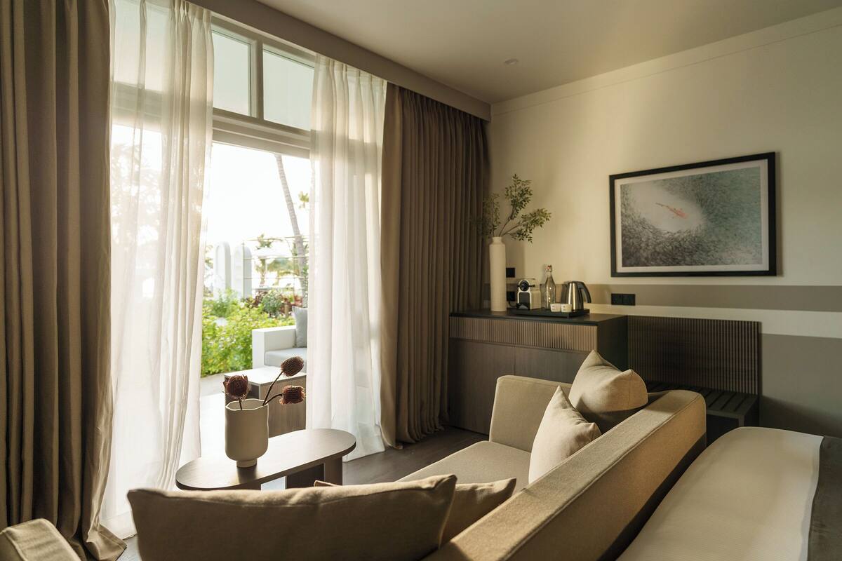 Una habitación de hotel moderna con sofá, una mesita y vistas a zonas verdes.