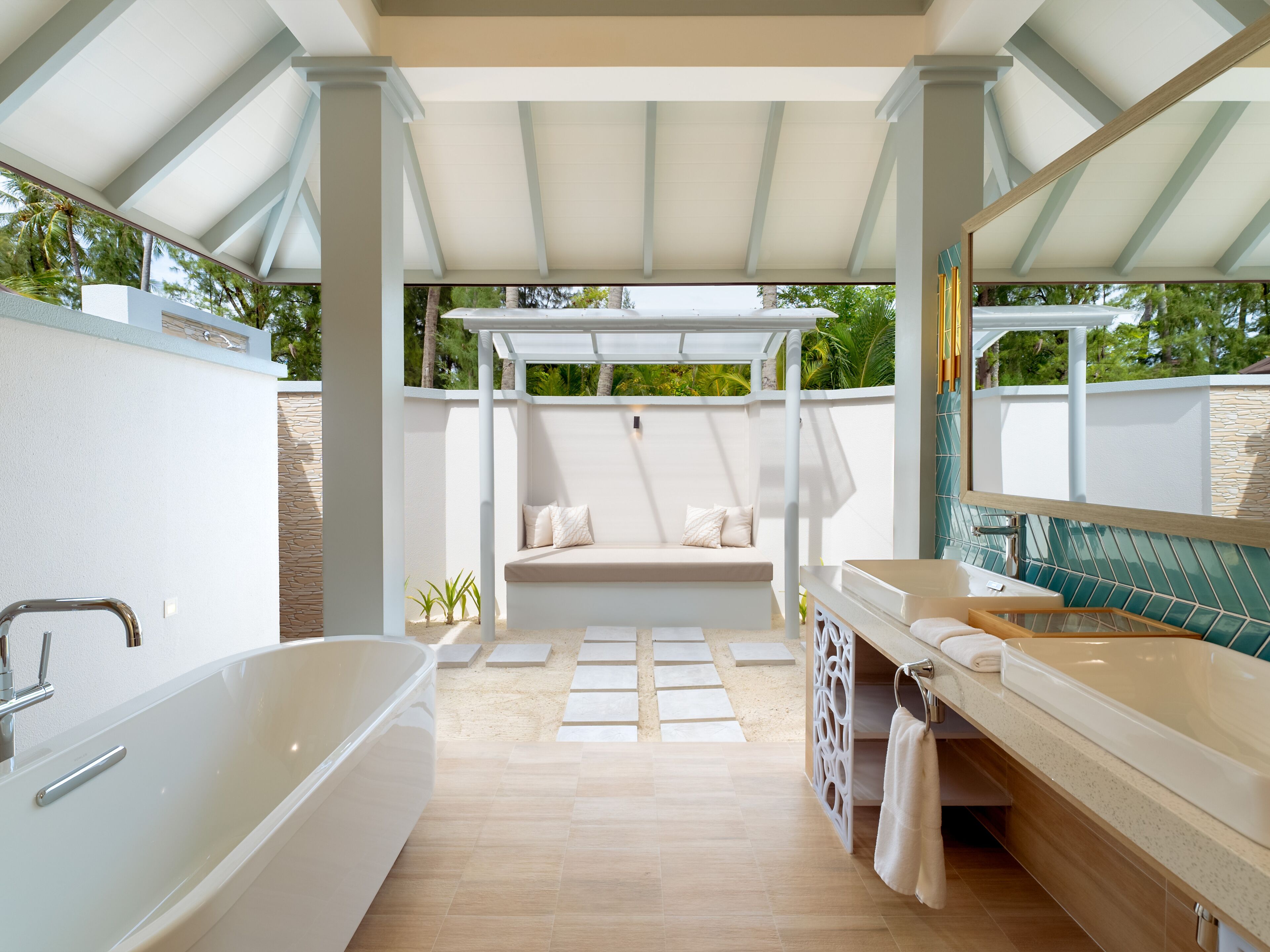 Un baño moderno con una bañera independiente, un tocador con espejo y una zona de estar bajo una pérgola.