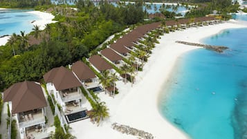A resort with multiple bungalow-style buildings, a white sandy beach, and a clear turquoise ocean.