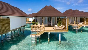 Des bungalows sur pilotis dotés de terrasses en bois, une eau turquoise cristalline et un ciel d’un bleu éclatant.