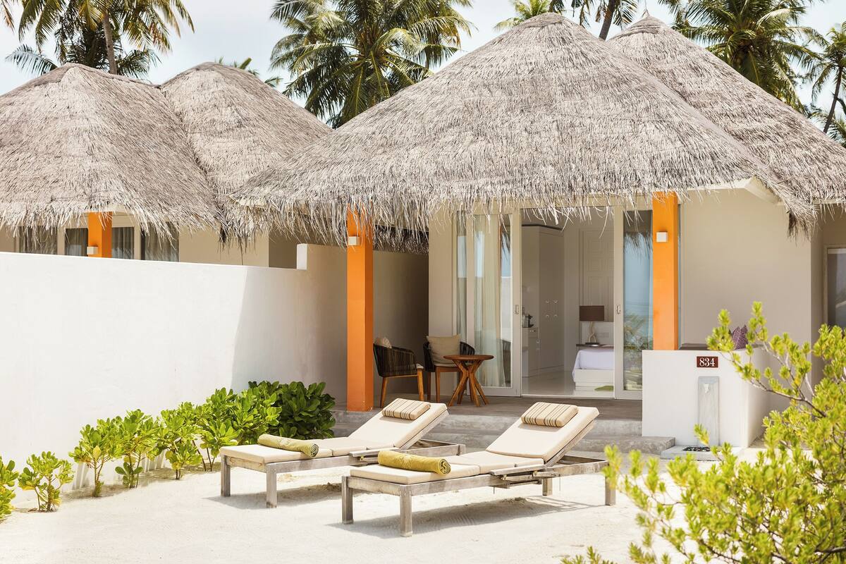 Un resort con construcciones de techo de paja, sillas de descanso y una pequeña zona de estar.