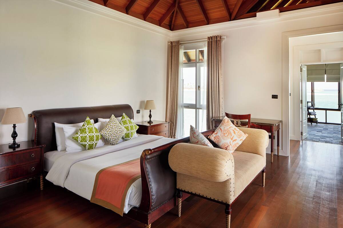 Un dormitorio amplio con una cama grande, una silla y una mesita de noche.
