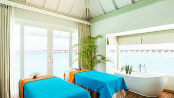 Relax in this serene room with a soothing sea view, featuring a bathtub and two massage tables.