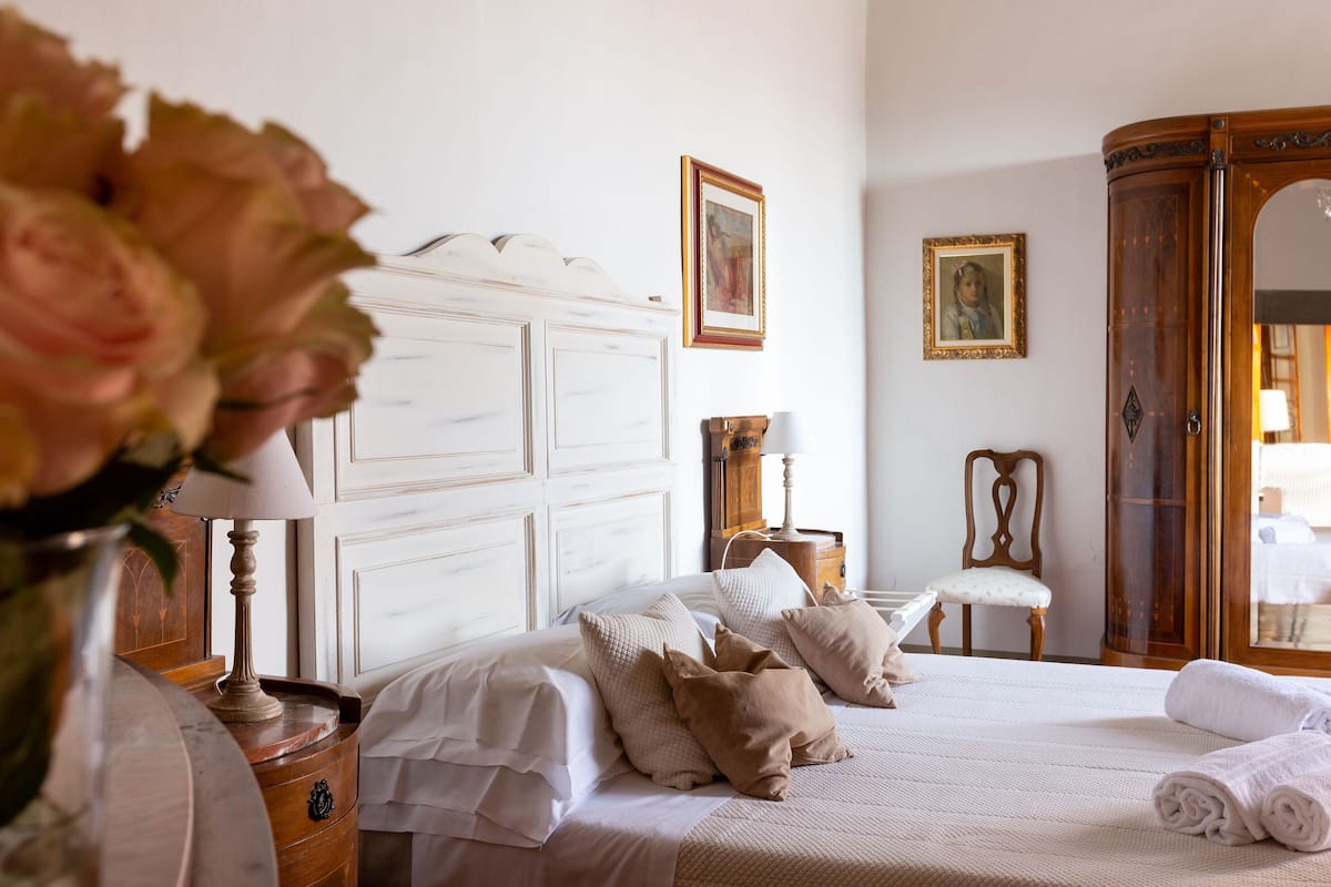 A neatly arranged bedroom with a bed, bedside tables, a wardrobe, and a chair.