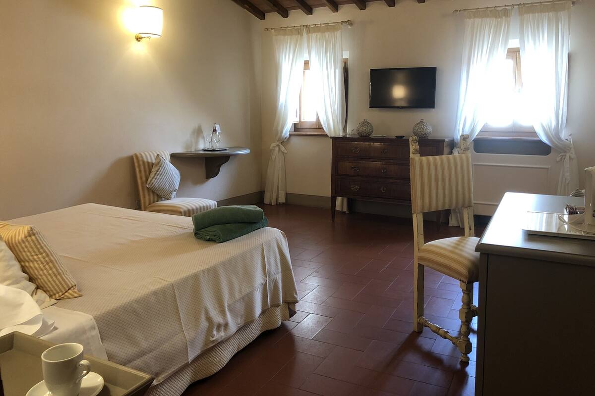 A hotel room with a bed, a desk, a chair, a dresser, and a television.
