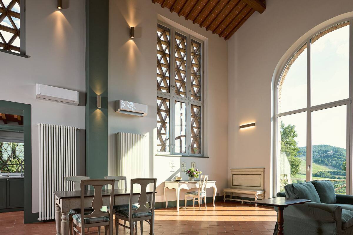 A spacious room with a dining area, a large window with a view of the countryside, and a cozy seating area.