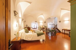 A spacious room with a bed, a desk, and a staircase. - Castello Vicchiomaggio (Greve in Chianti)