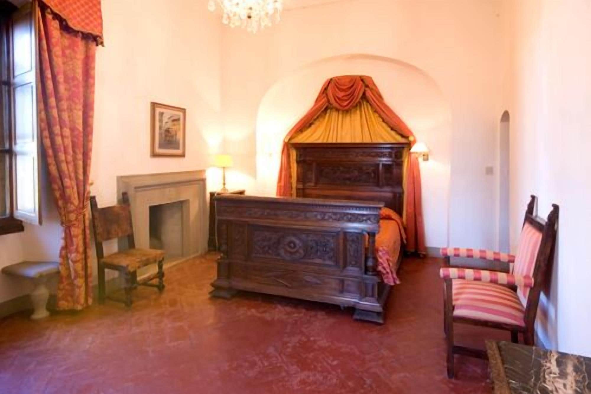 Une chambre à coucher de style traditionnel, avec un lit à baldaquin, une cheminée, un fauteuil et un lustre.