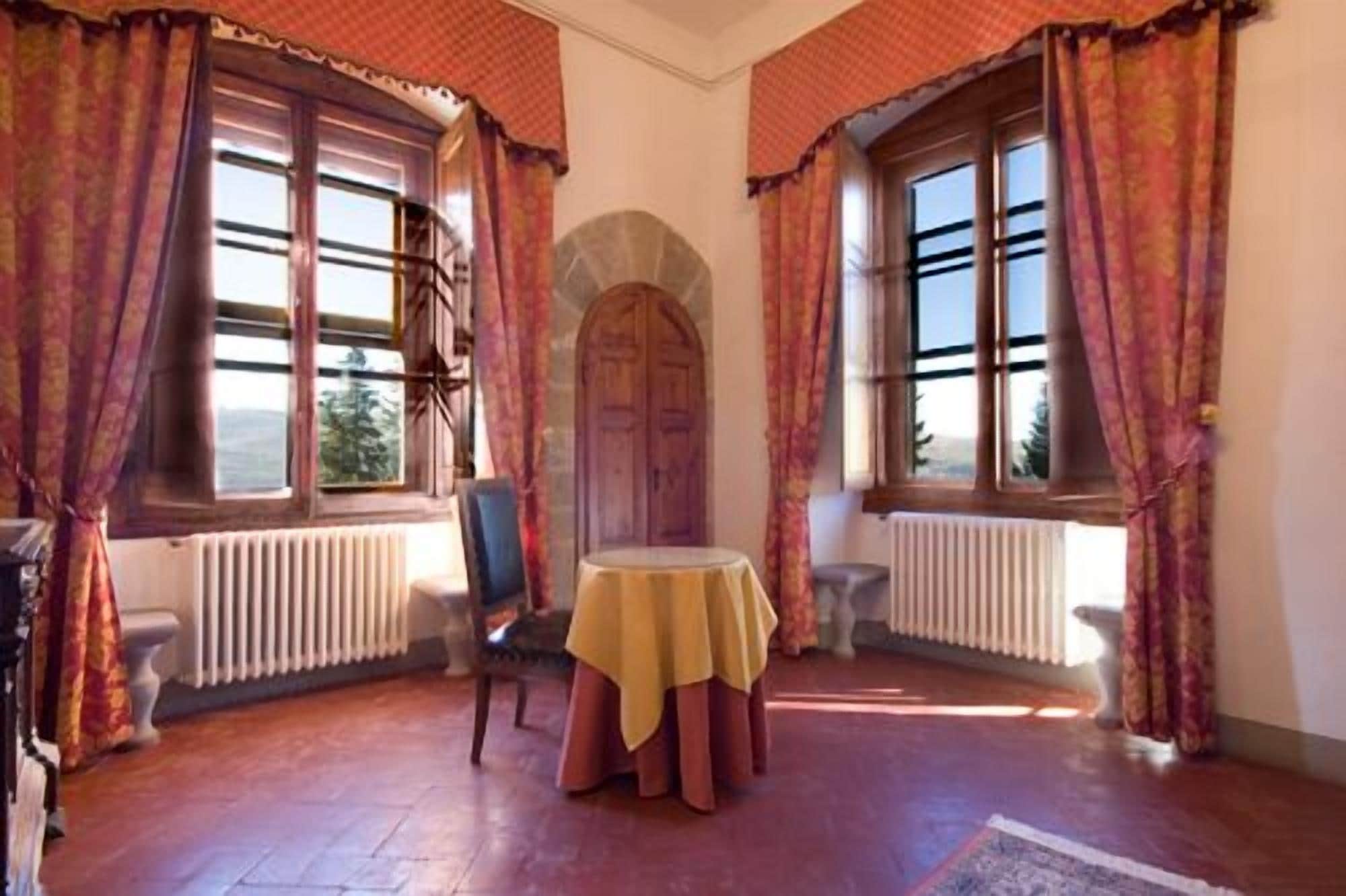 A room with a round table, two chairs, a radiator, and a large arched doorway.