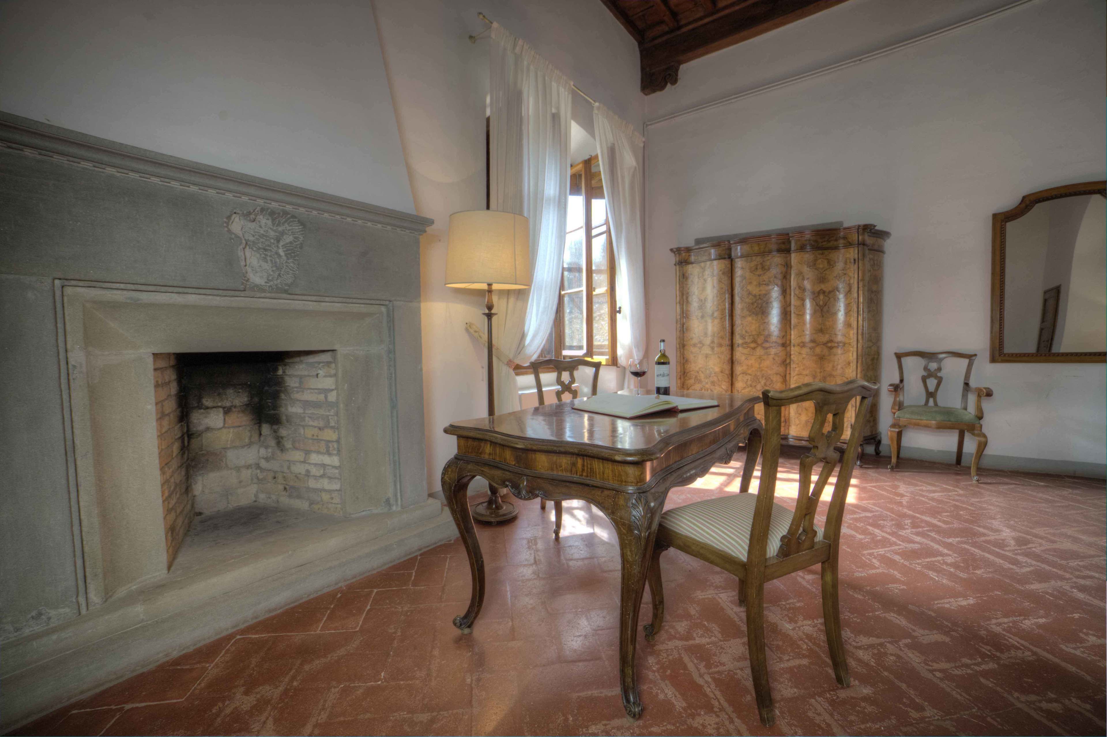 A room with a fireplace, a table, chairs, a lamp, and a mirror.