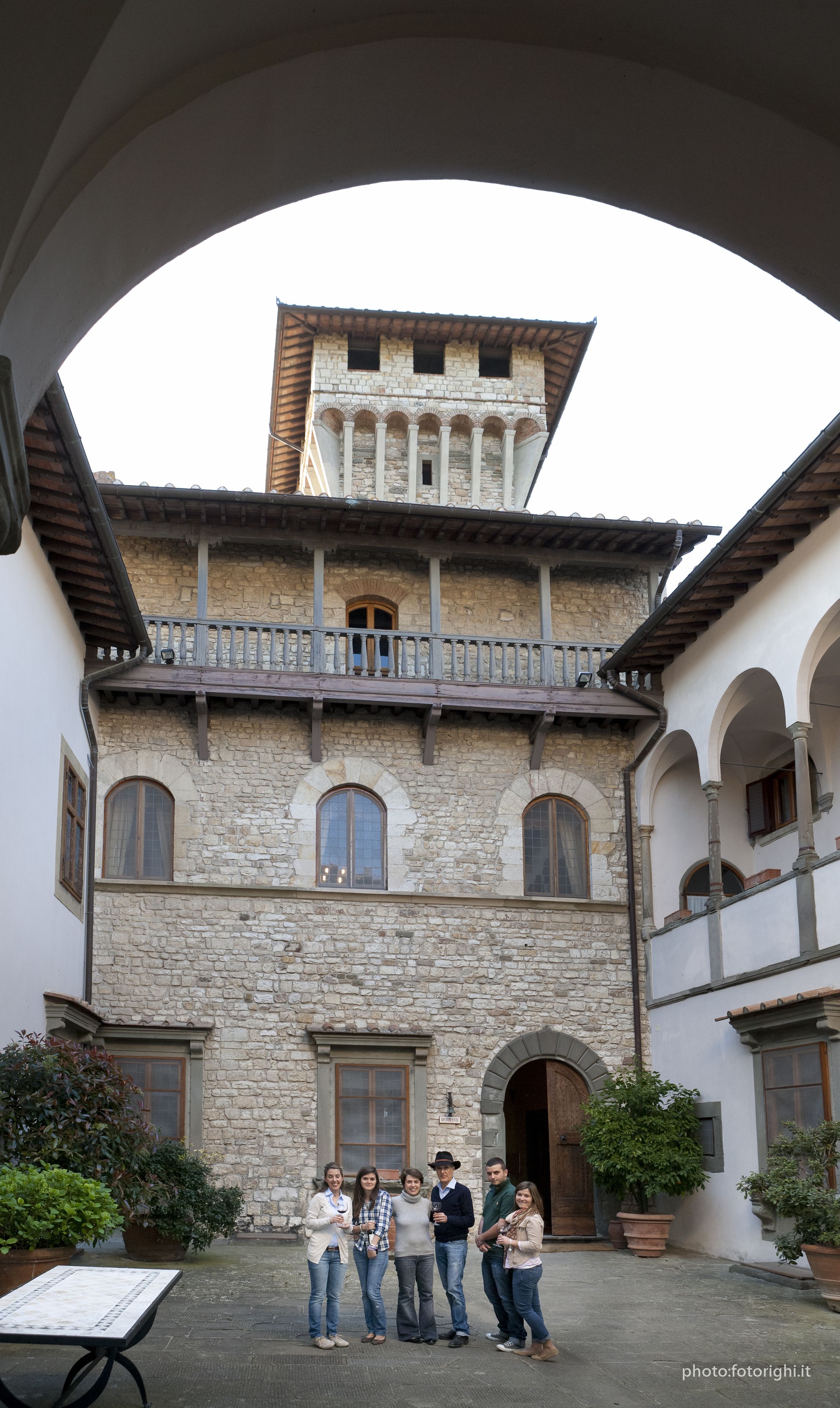 A courtyard with a stone building featuring arched windows and a balcony.
