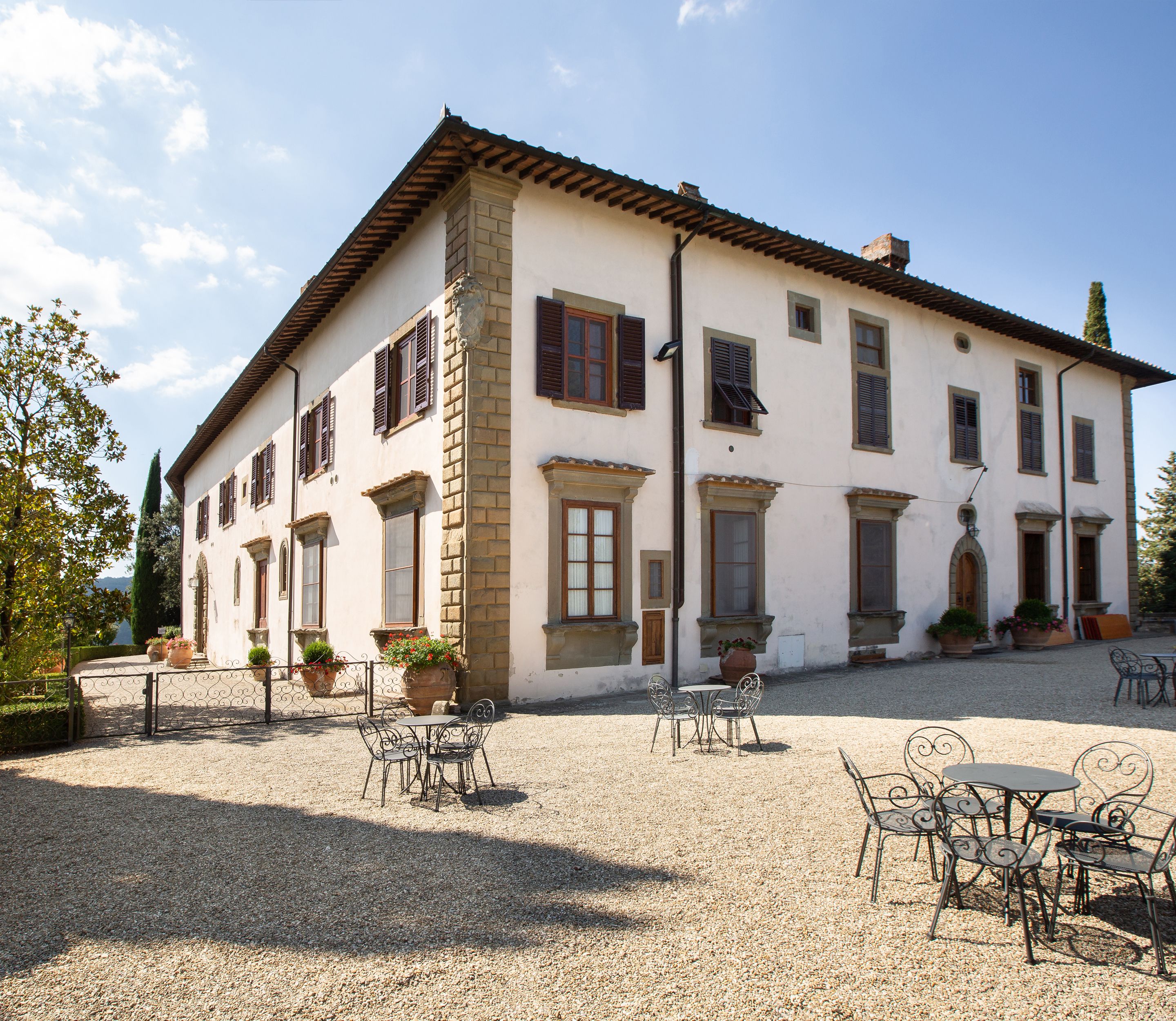 A two-story building with a courtyard featuring outdoor seating and potted plants.