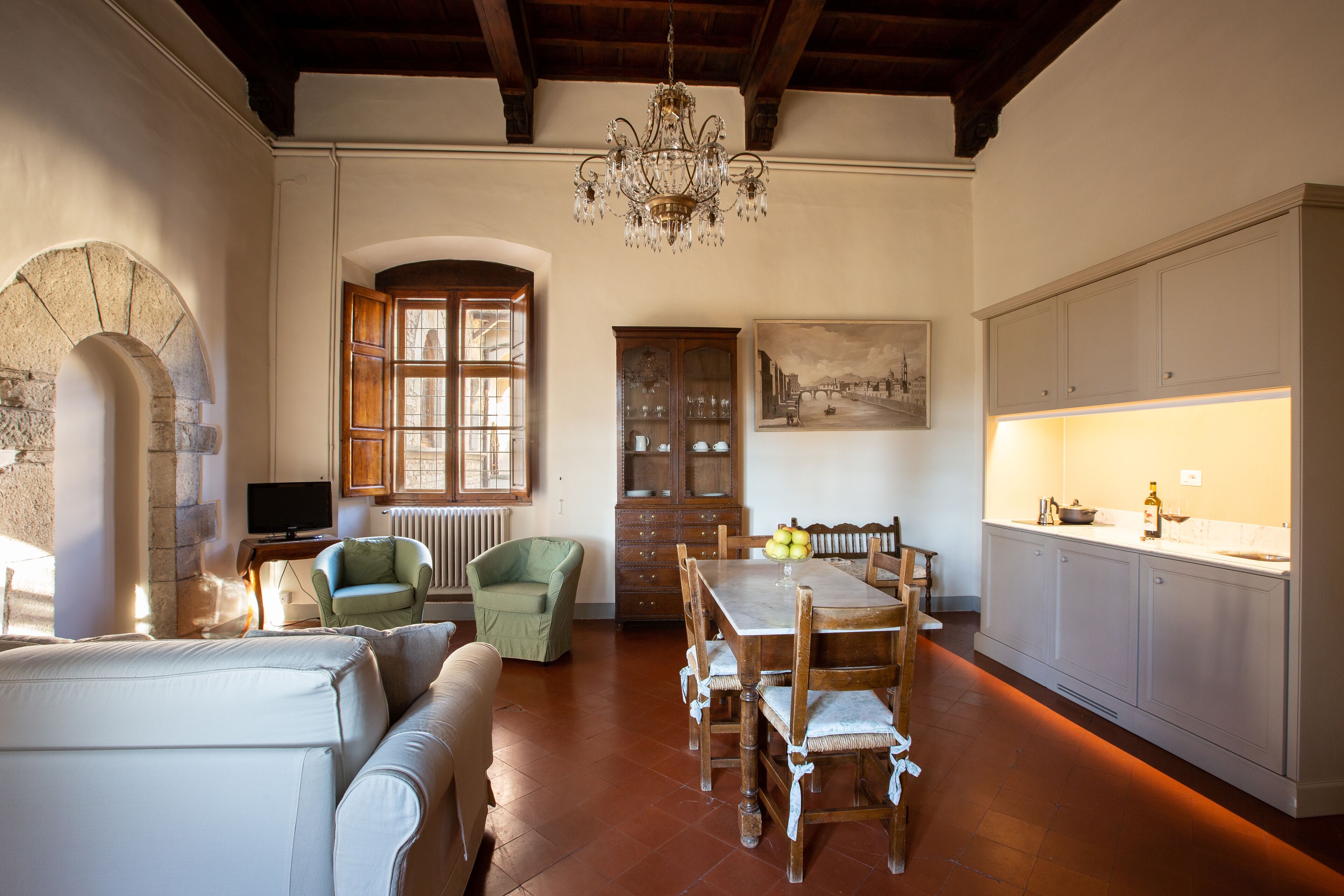 A spacious living room with a wooden dining table, a green armchair, and a sofa.