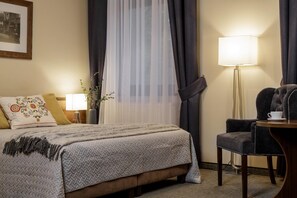 A hotel room with a bed, a chair, a lamp, and a window with sheer curtains. - Villa Vita (Zakopane)