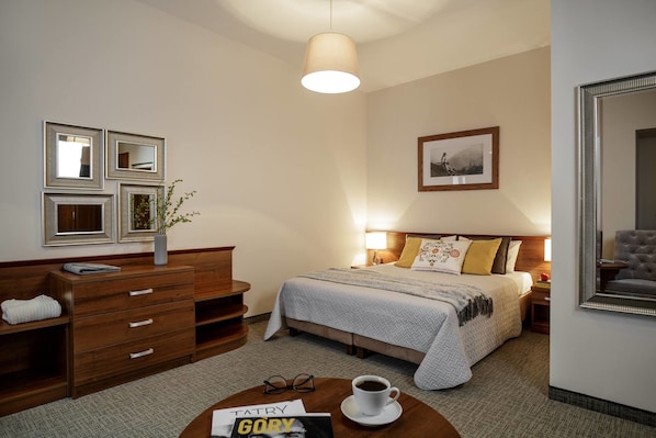 A hotel room with a bed, bedside table, lamp, dresser, and a framed picture on the wall. - Villa Vita (Zakopane)