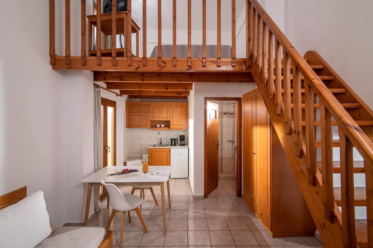 Amplia sala de estar con escalera de madera, una mesa de comedor con sillas y una cocina con armarios de madera.