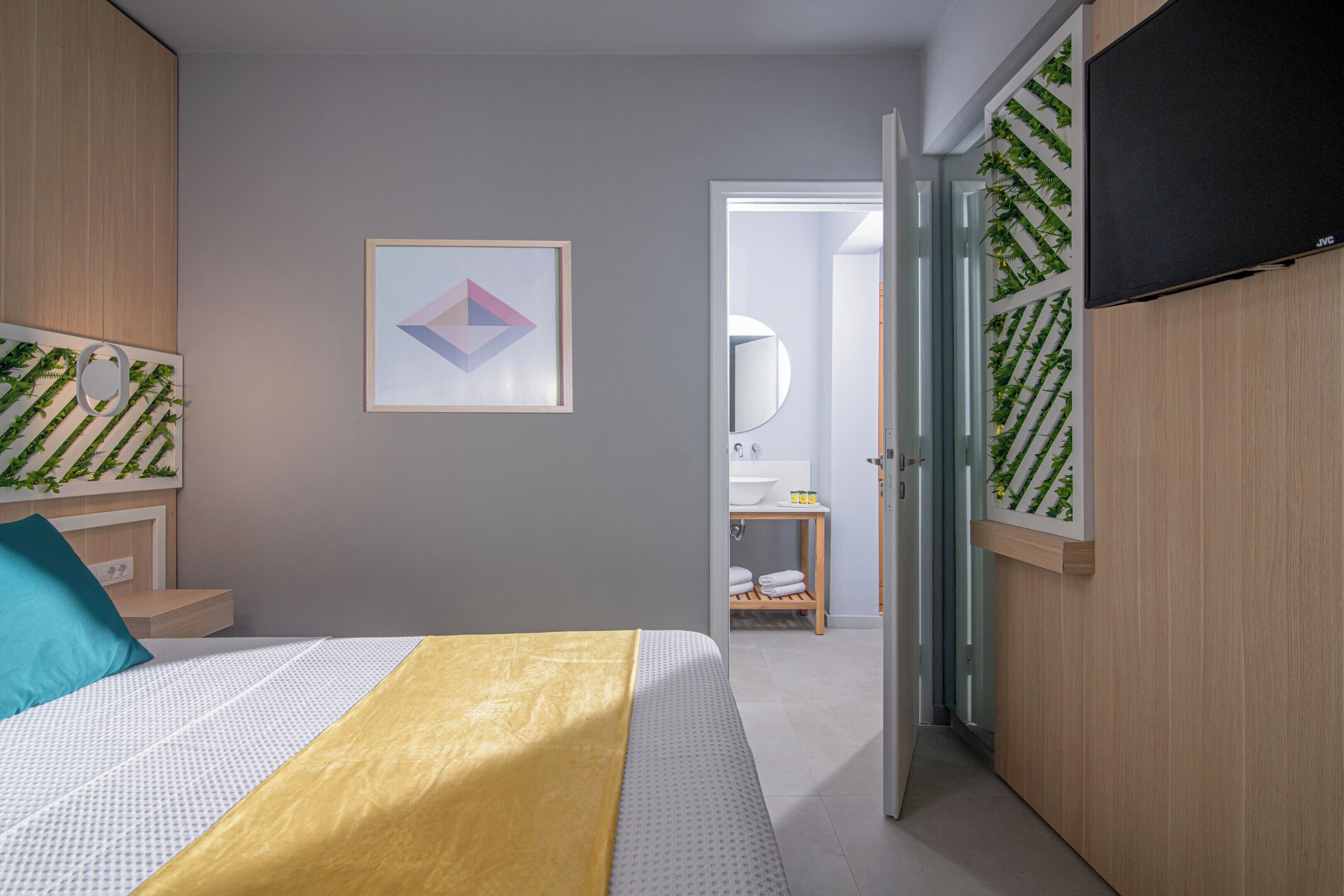 Ein Schlafzimmer mit einem Bett, einem Nachttisch, einem Spiegel und einer Tür zu einem Badezimmer.