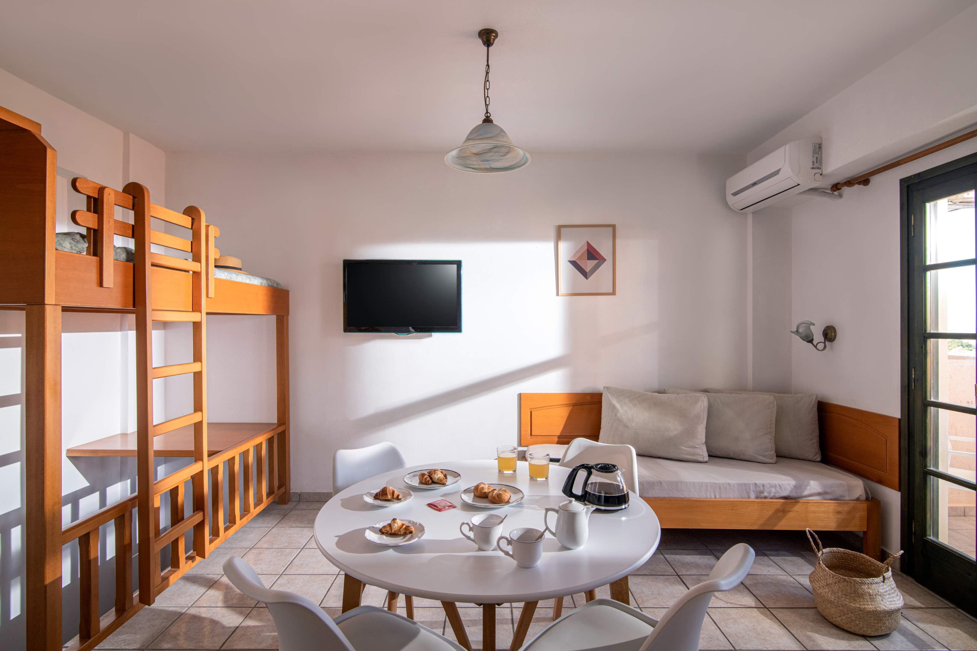 Una habitación compacta con literas, televisión, mesa de comedor y desayuno, y un sofá.