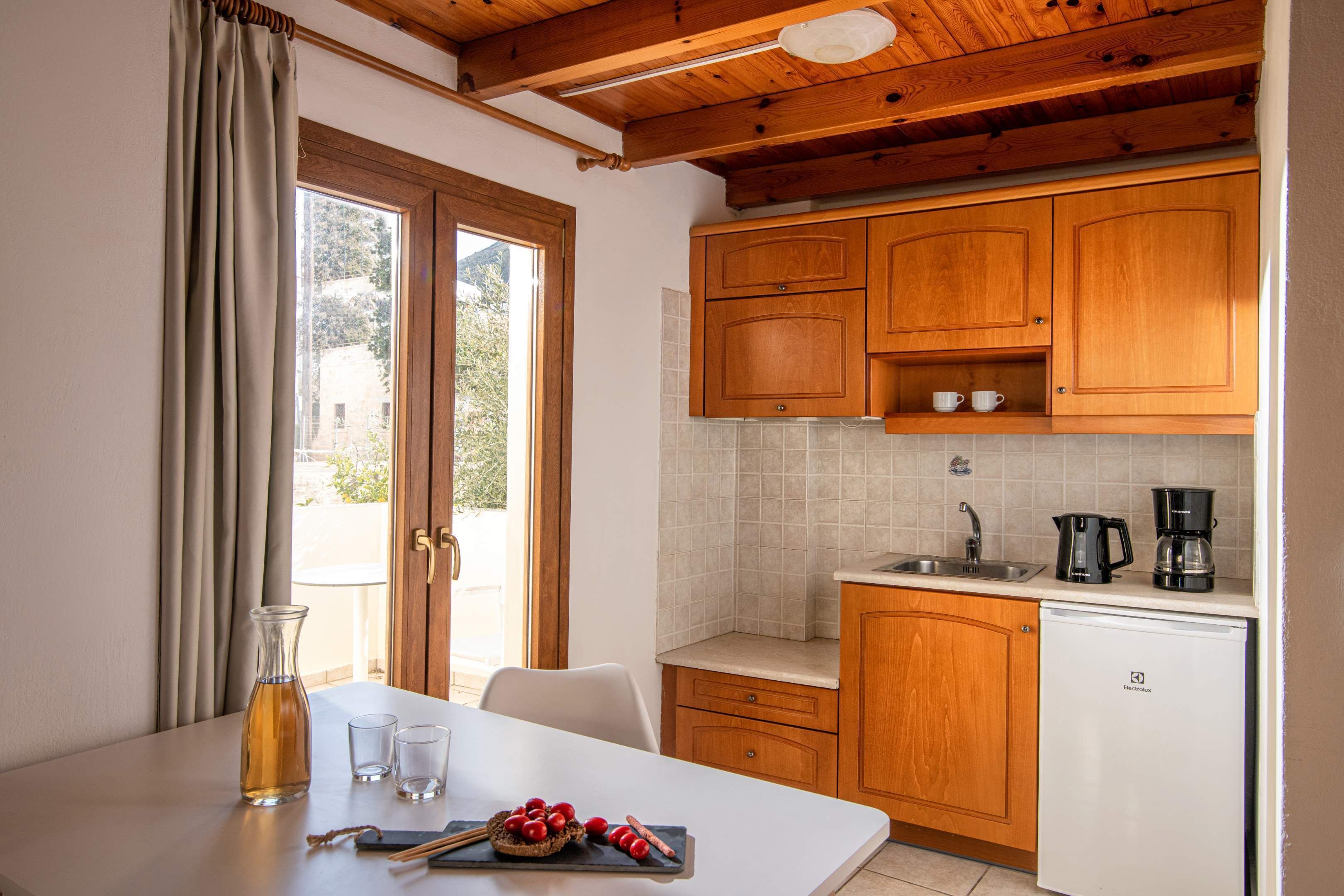 A compact kitchen with wooden cabinets, a white countertop, a sink, and a coffee maker.