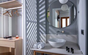A modern bathroom with a white sink, a round mirror, and a wooden vanity. - Villa Elite by Checkin (Hersonissos)