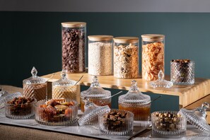 A variety of food items displayed in glass containers on a wooden table against a teal wall. - Villa Elite by Checkin (Hersonissos)