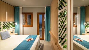 A modern hotel room with two beds, a sliding glass door to the balcony, and a wall-mounted plant display. - Villa Elite by Checkin (Hersonissos)