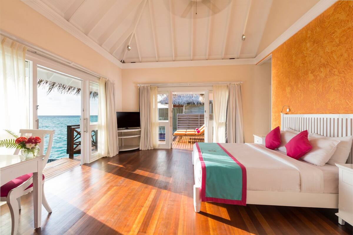 Ein Schlafzimmer mit Bett, Schreibtisch und Meerblick.