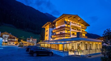 A multi-story hotel with a restaurant on the ground floor, surrounded by a mountainous landscape.