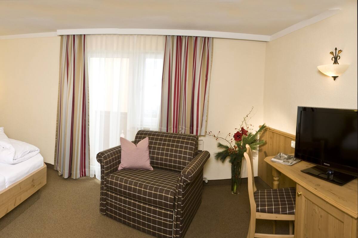 Una habitación de hotel con cama, sofá, televisor y escritorio.