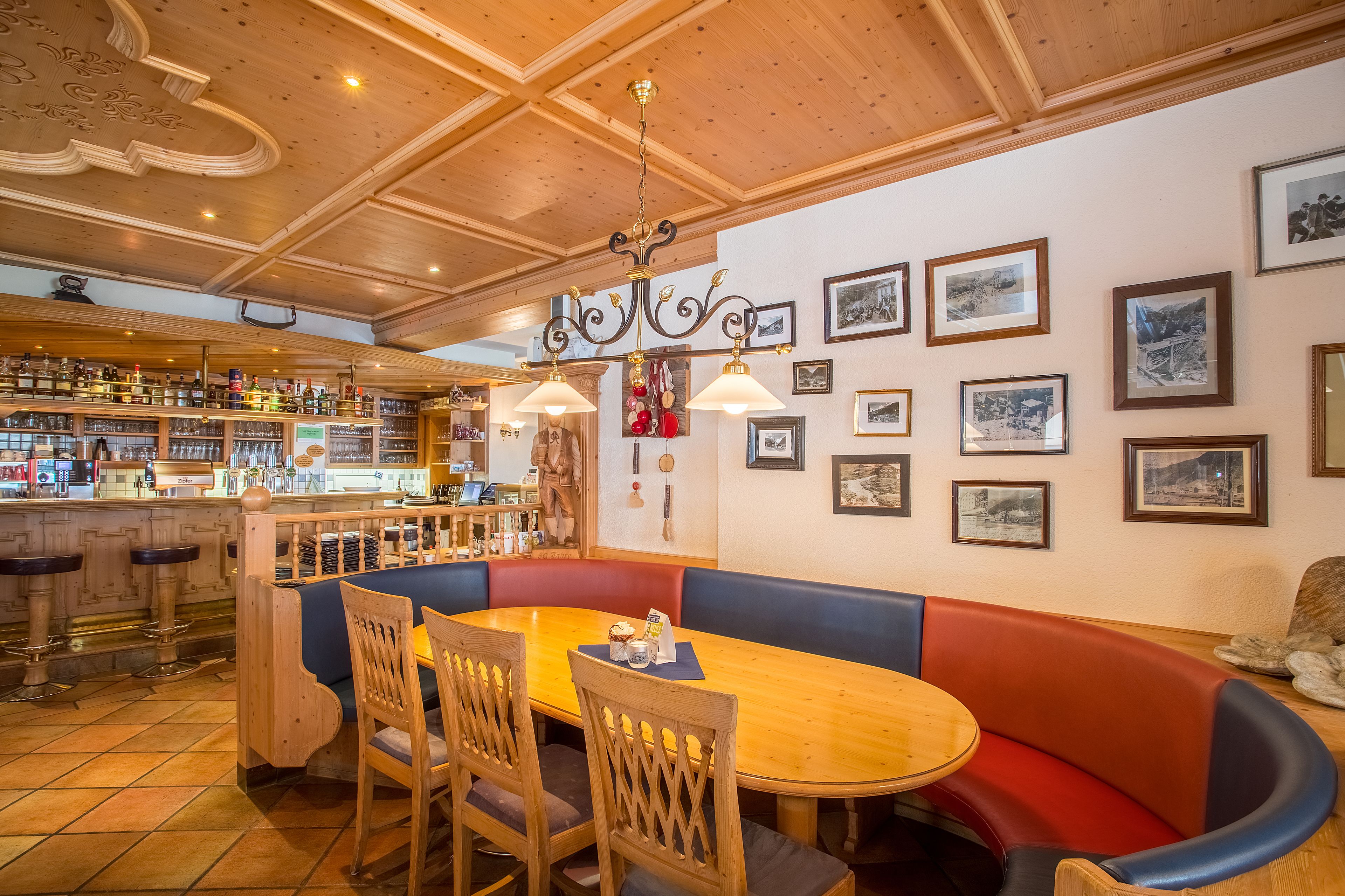 Een restaurant met een houten inrichting, een bar en een eetgedeelte met een zitgeul en stoelen.