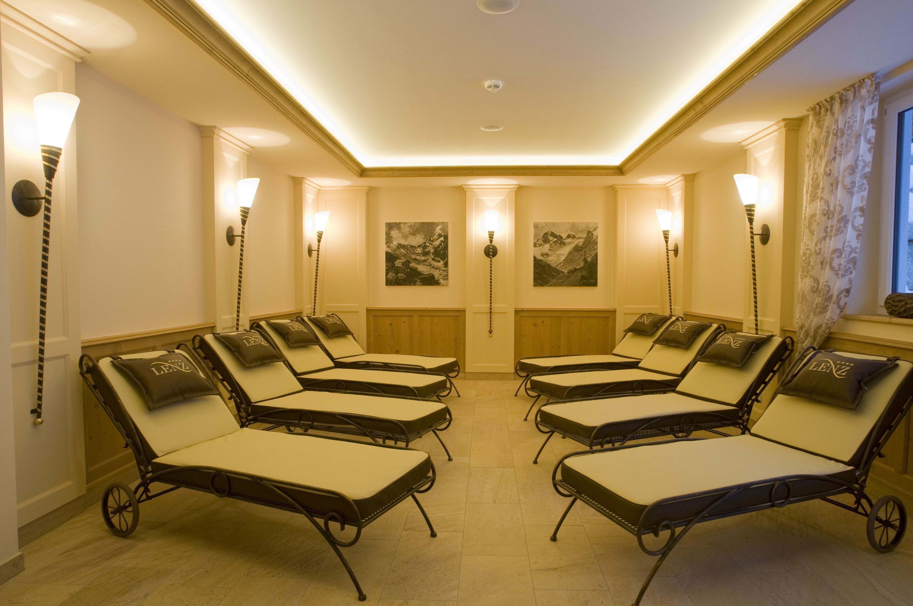 A room with six lounge chairs arranged in two rows, each with a pillow and a wall-mounted lamp.