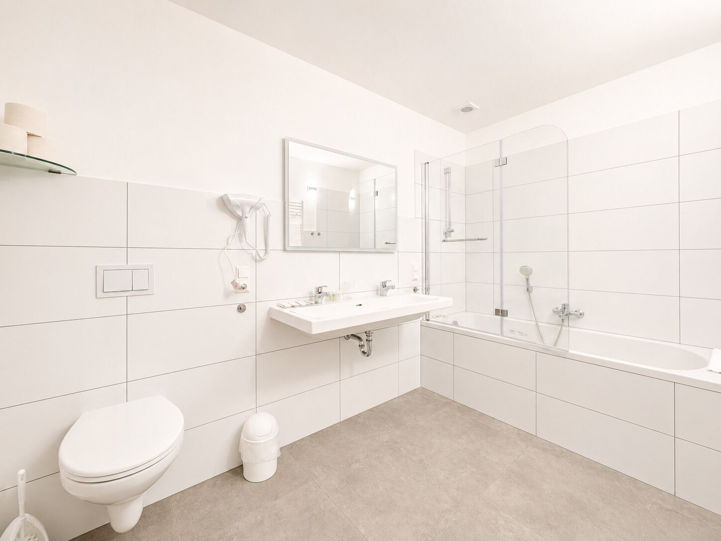 A modern bathroom with a toilet, sink, mirror, and shower.