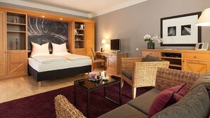 Une chambre d’hôtel équipée d’un lit, d’un bureau, d’une chaise, d’un canapé et d’une télévision.