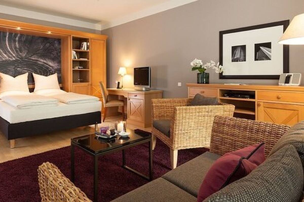 A hotel room with a bed, a desk, a chair, a sofa, and a TV.