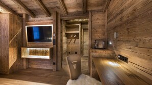 Un intérieur en bois avec un téléviseur fixé au mur, un banc en bois et un fauteuil recouvert de fourrure.