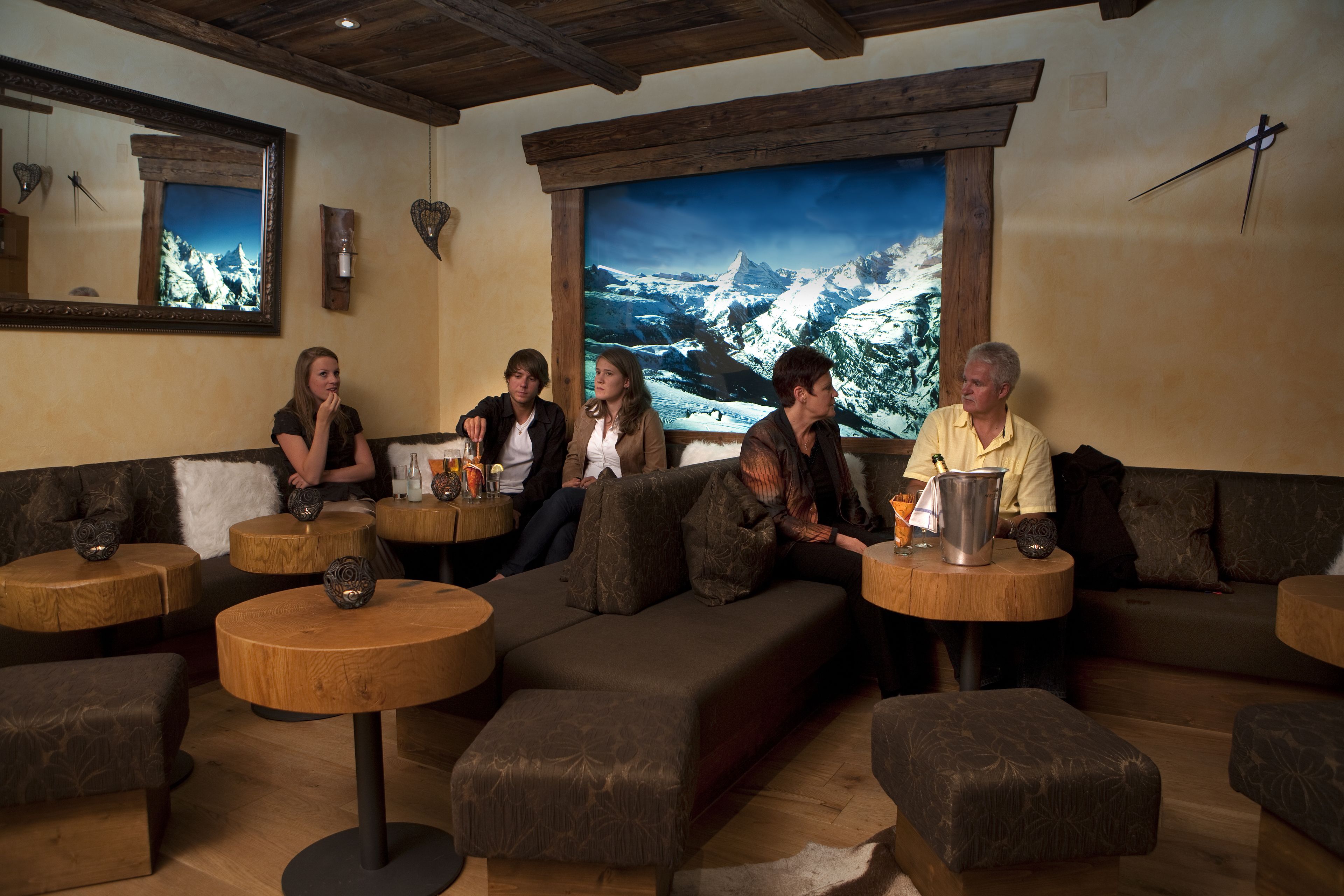 Un'accogliente area relax con divani e tavoli rotondi, un'ampia finestra con vista sulle montagne e un soffitto in legno.