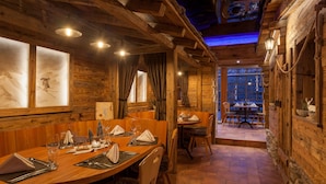Un intérieur en bois comprenant un coin repas, des murs en bois et une vue par une fenêtre.