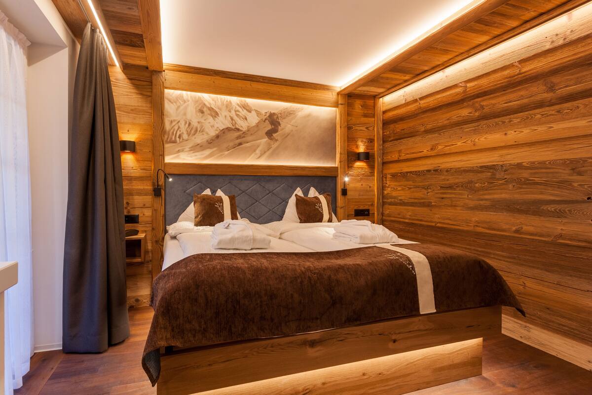 Ein Schlafzimmer mit Holzwänden, einem Bett, einem großen gerahmten Bild an der Wand und zwei Nachttischlampen.