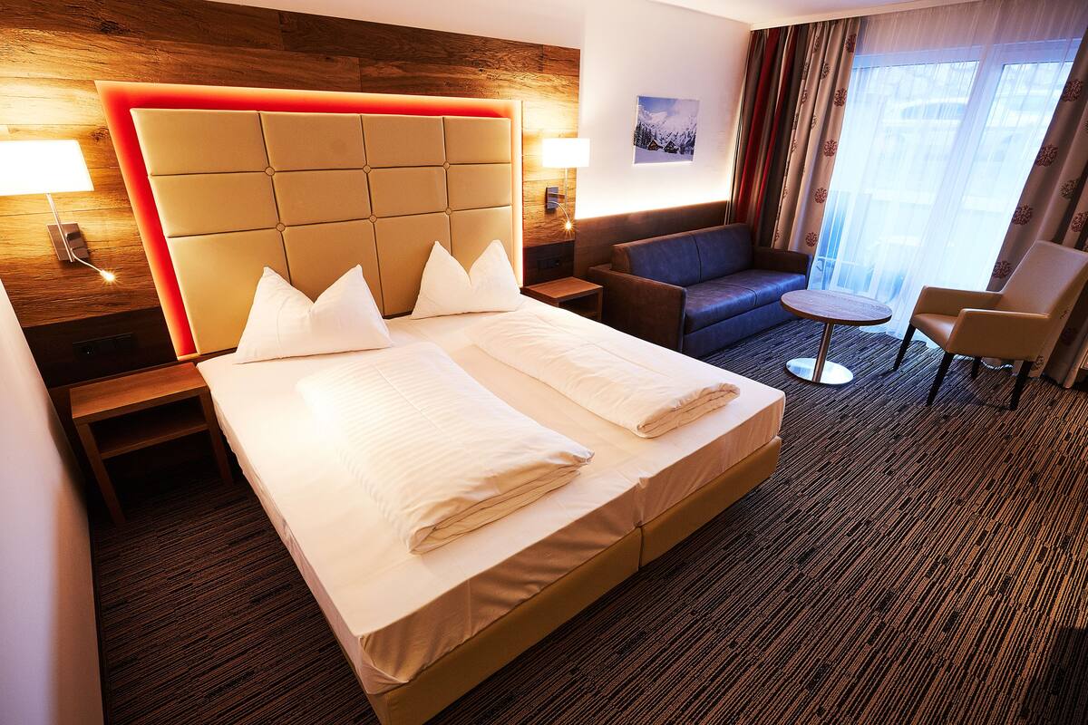 Una habitación de hotel con una cama grande, un sofá, una silla y una mesita.