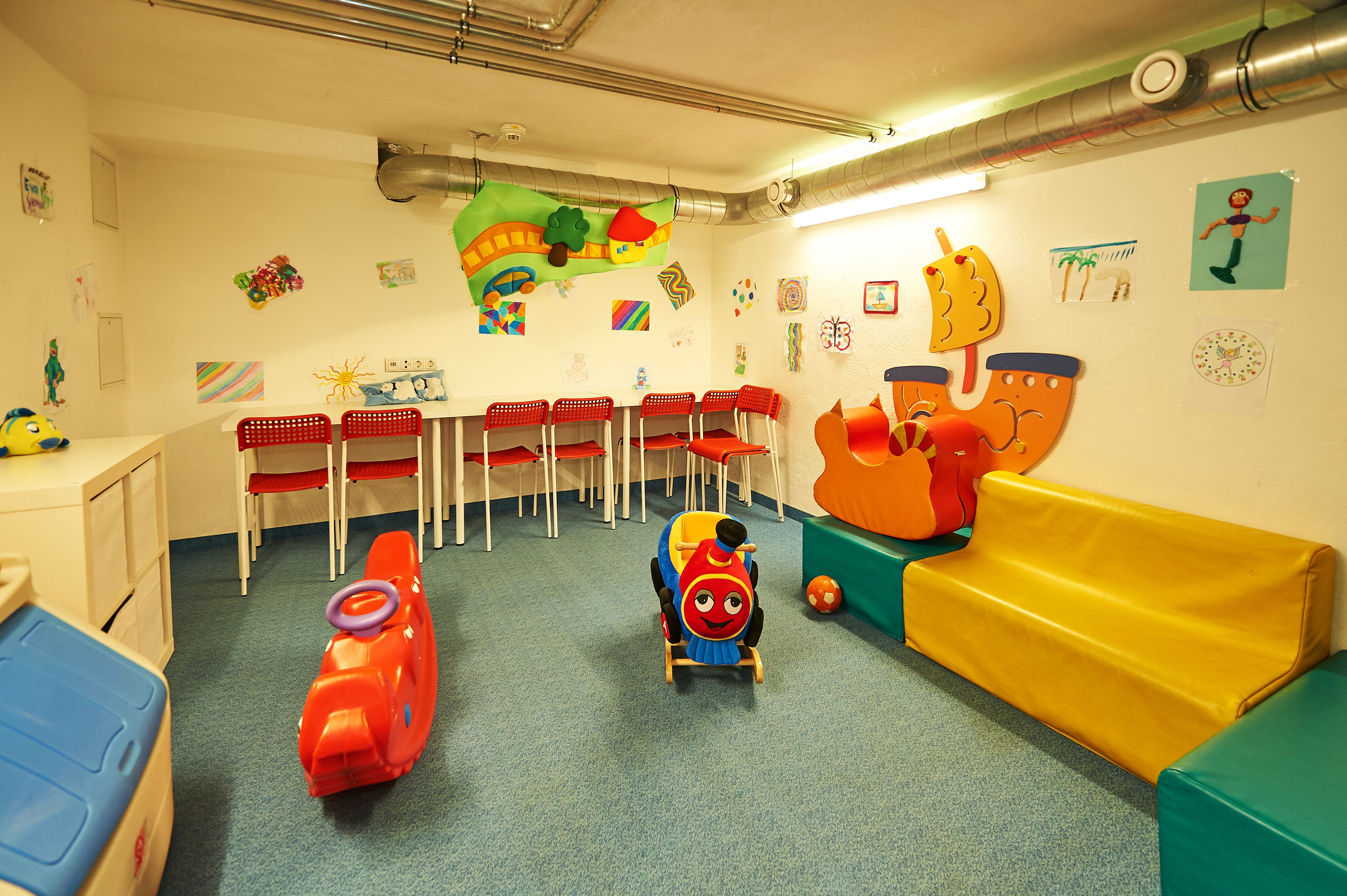 A children's playroom with colorful toys, a play table, and a sofa.
