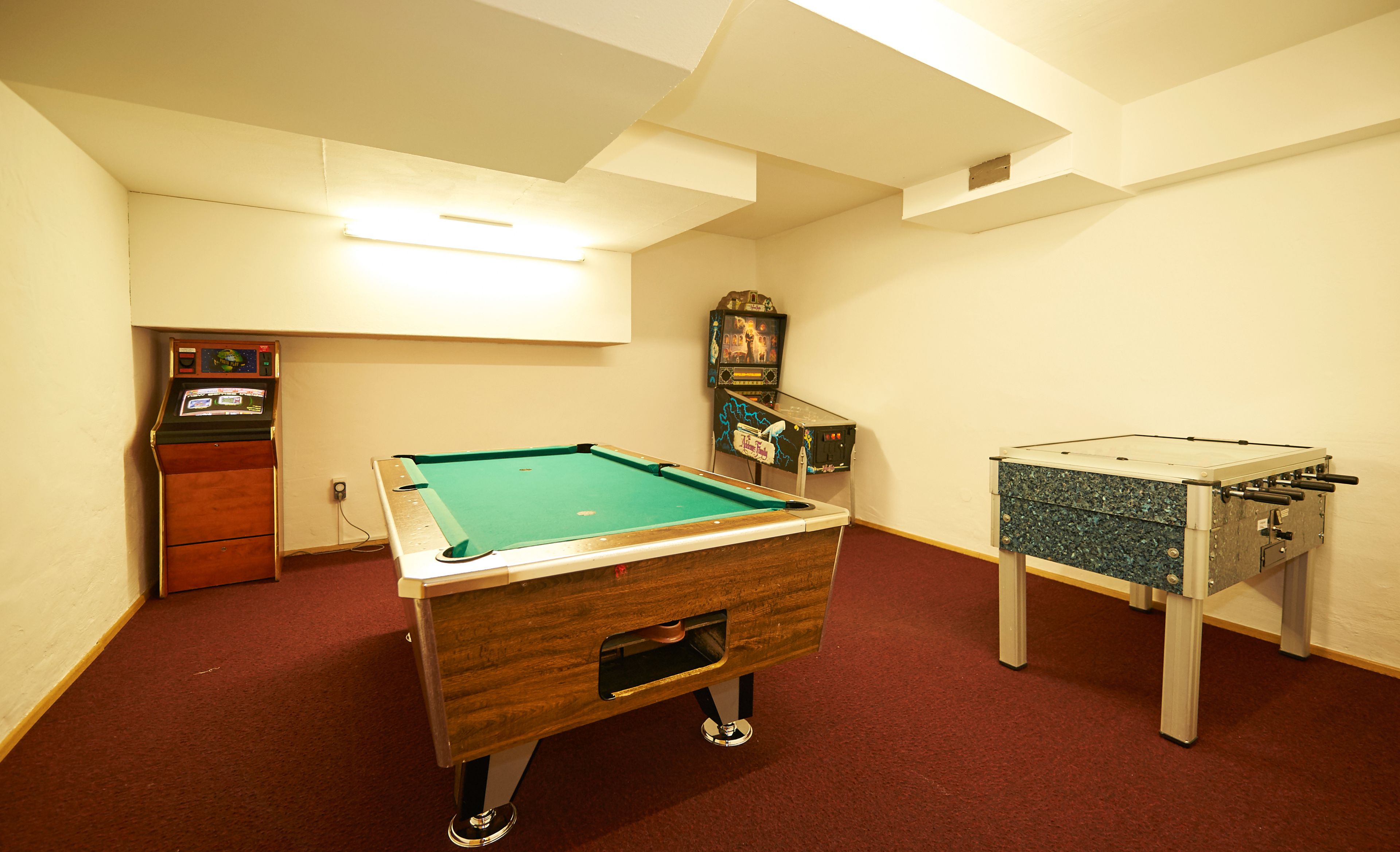 Una habitación con mesa de billar, mesa de futbolín y jukebox.
