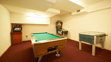 Una habitación con mesa de billar, mesa de futbolín y jukebox.