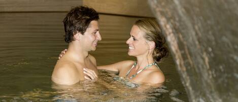 A couple in a hot tub with a water feature.