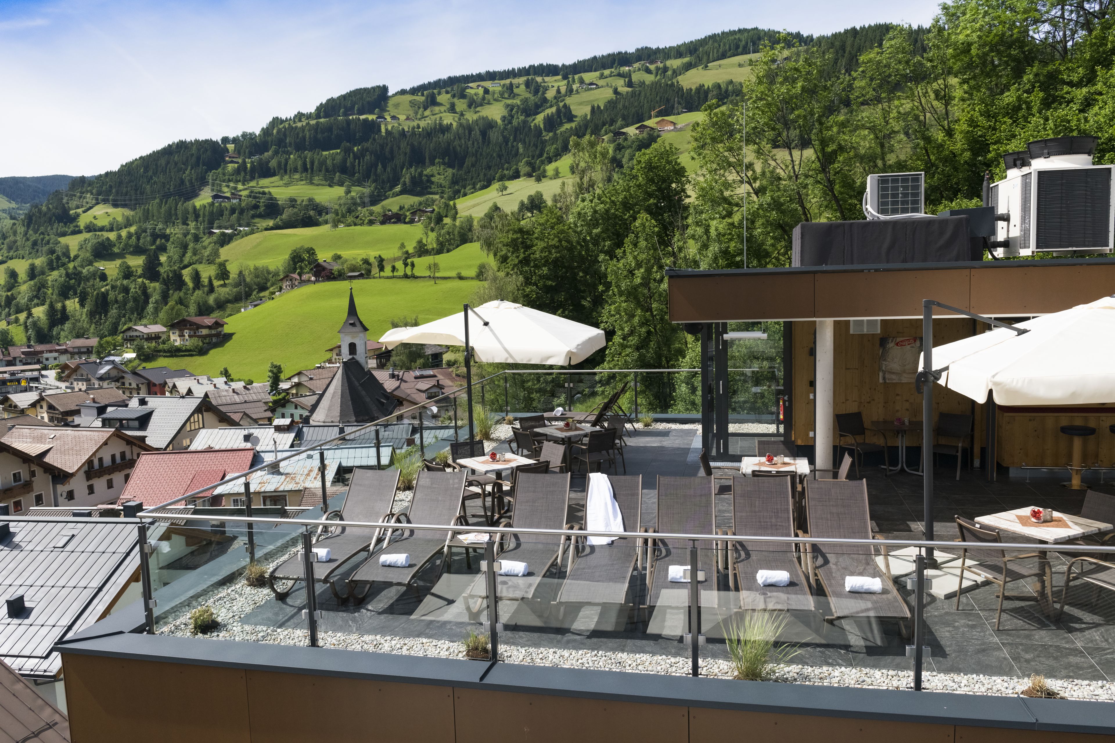 Une terrasse sur le toit, dotée d’un espace extérieur aménagé, offrant une vue panoramique sur un village pittoresque et les collines environnantes.